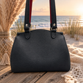 Front view of black handbag with dual shoulder straps and red accents