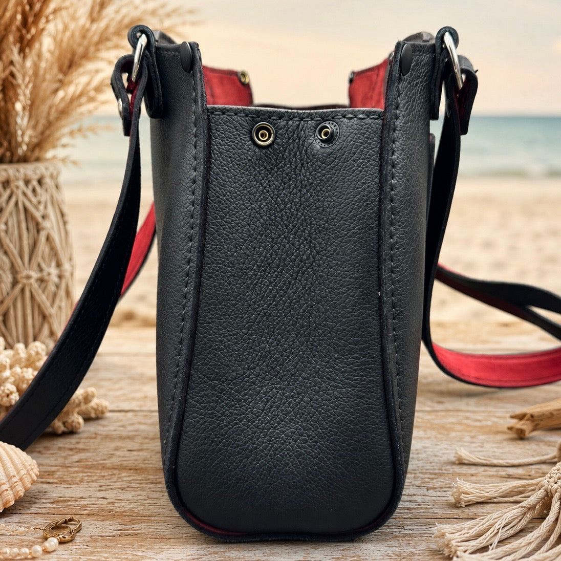 Side view of structured black handbag with red strap lining