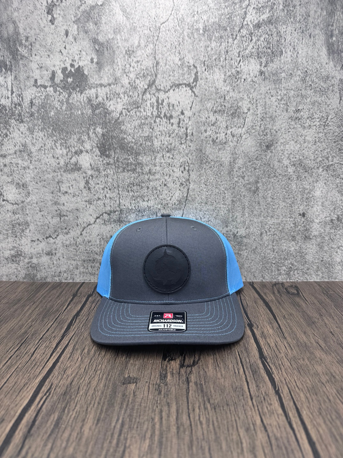 Front view of charcoal and blue Richardson 112 hat with black leather hammerhead shark patch